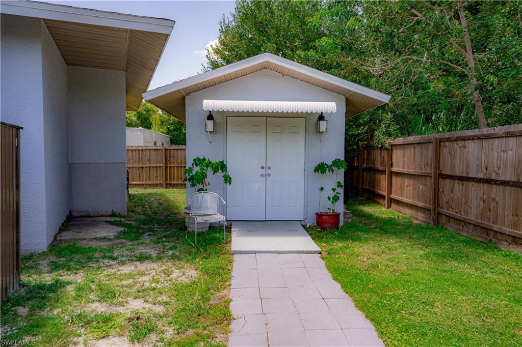 Exterior storage building with double white doors, an awning, and two wall-mounted light fixtures