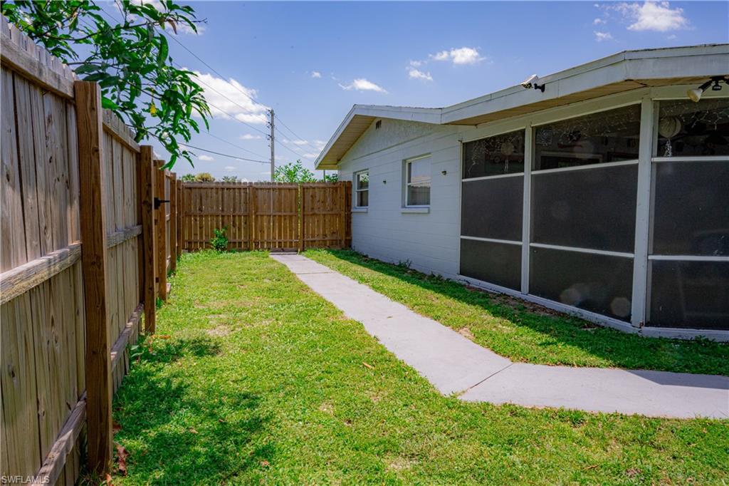 Expansive grassy yard with wood fencing and a concrete pathway