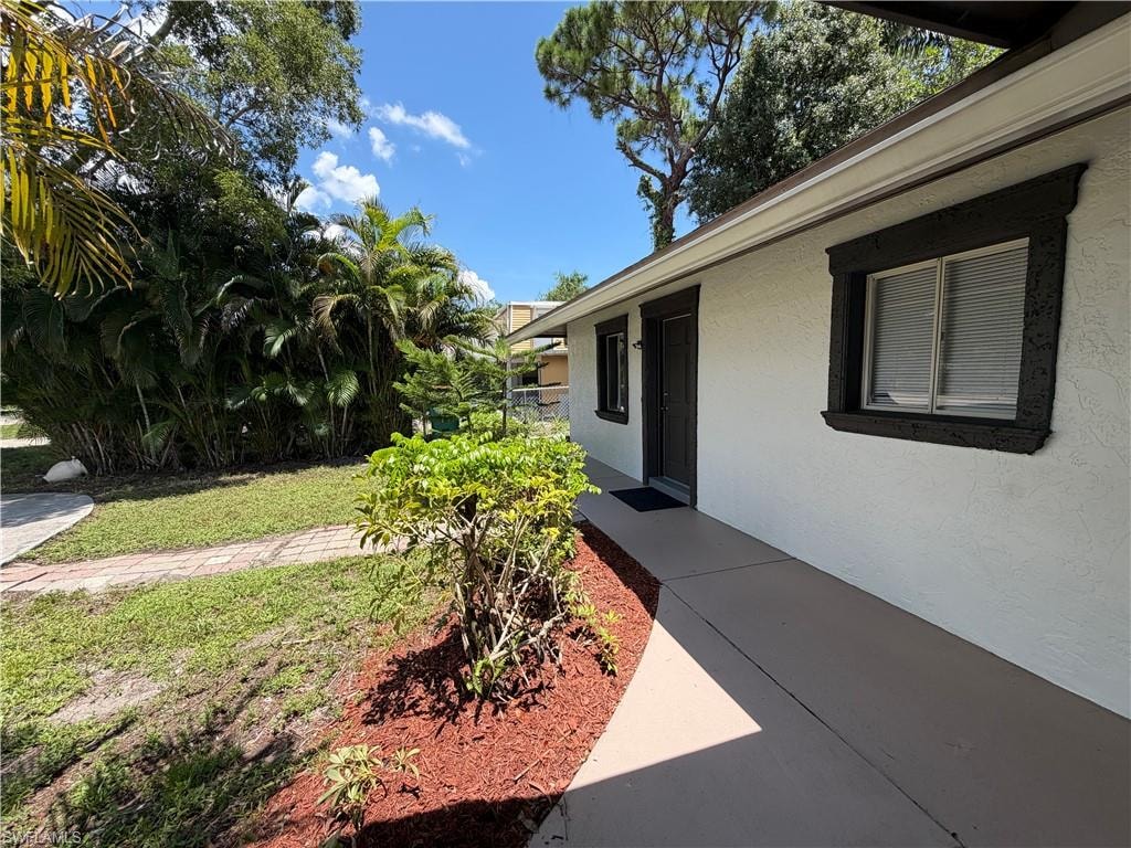 White stucco exterior with dark trim and a covered entry