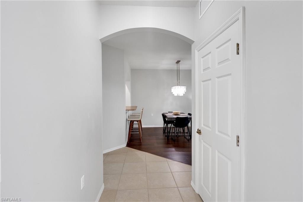 Archway entry, tile flooring, wood-finish flooring, paneled interior door, suspended lighting fixture