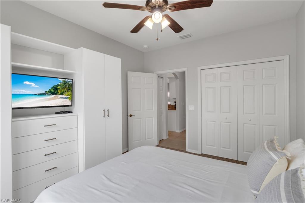 Built-in cabinetry with integrated shelving and drawers, ceiling fan with light fixture, and paneled bi-fold closet doors