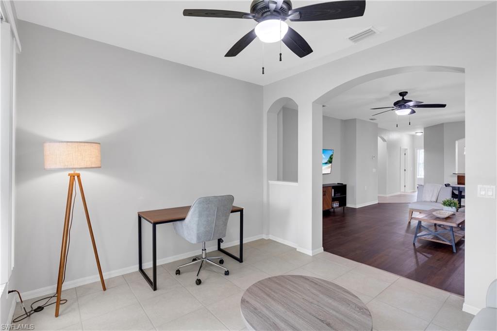 Recessed wall niches, arched doorways, tiled flooring, wood-finish flooring, and ceiling fans with integrated lighting