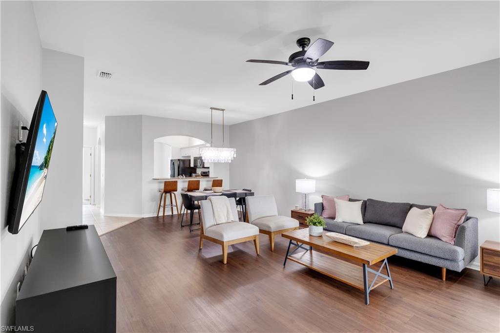 Wood-finish flooring throughout, vaulted ceilings, a ceiling fan with integrated lighting, and an arched entryway