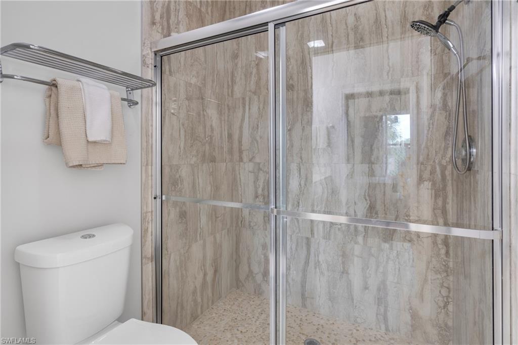 Enclosed shower with sliding glass doors, stone-finish shower walls, and a pebble tile shower floor