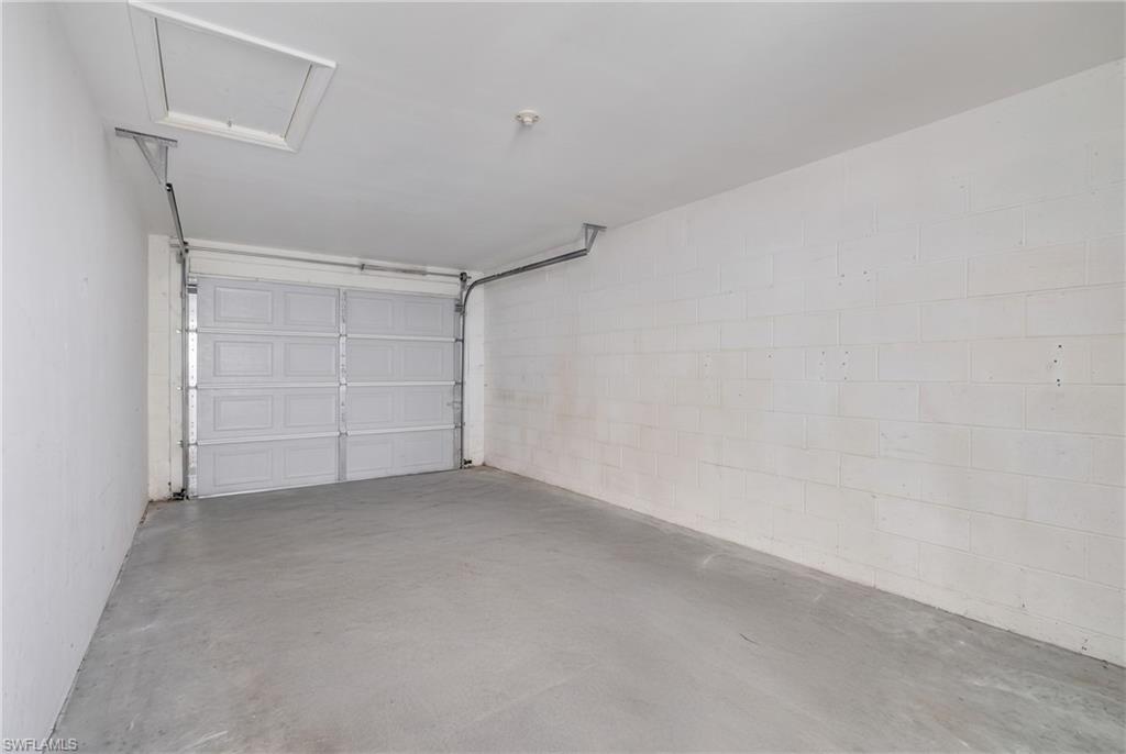 Spacious garage featuring a white sectional overhead door, concrete flooring, and skylights for natural illumination