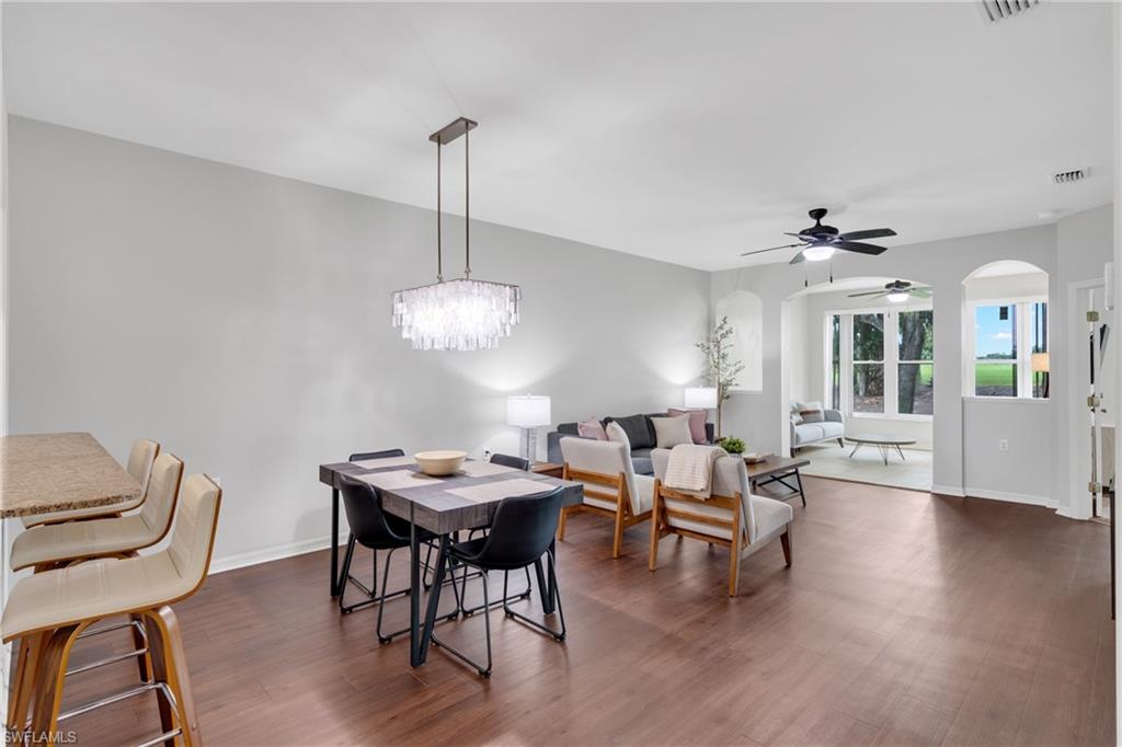 Open-concept living area showcasing hardwood flooring throughout, a modern pendant light fixture with crystal detailing, and seamless sightlines to a bright foyer with French doors