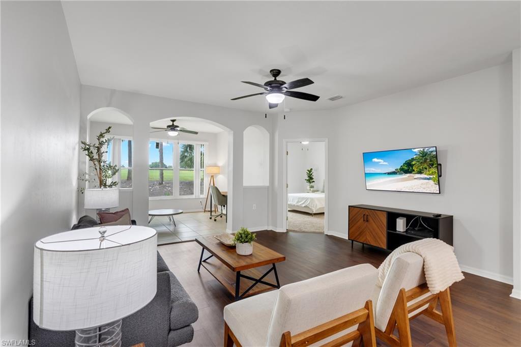 Open-concept living area featuring hardwood flooring, a ceiling fan with integrated lighting, and a wall-mounted flat-screen television