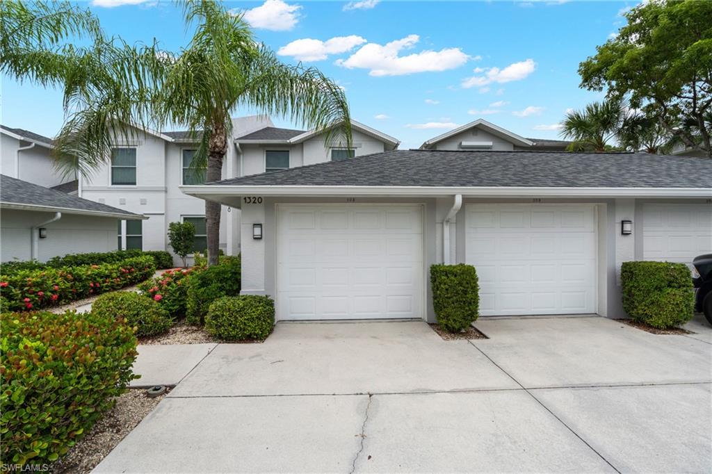 Detached private garages, lush landscaping, exterior wall lighting, and shingle roofing