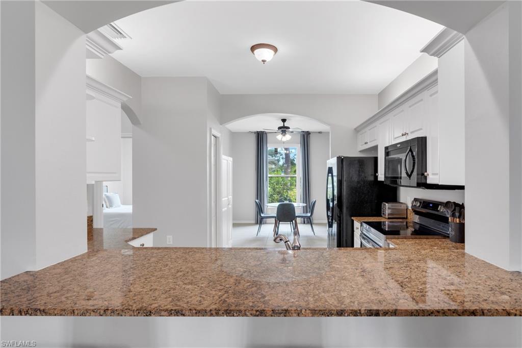 Kitchen featuring granite-look countertops, white upper and lower cabinetry, and black appliances