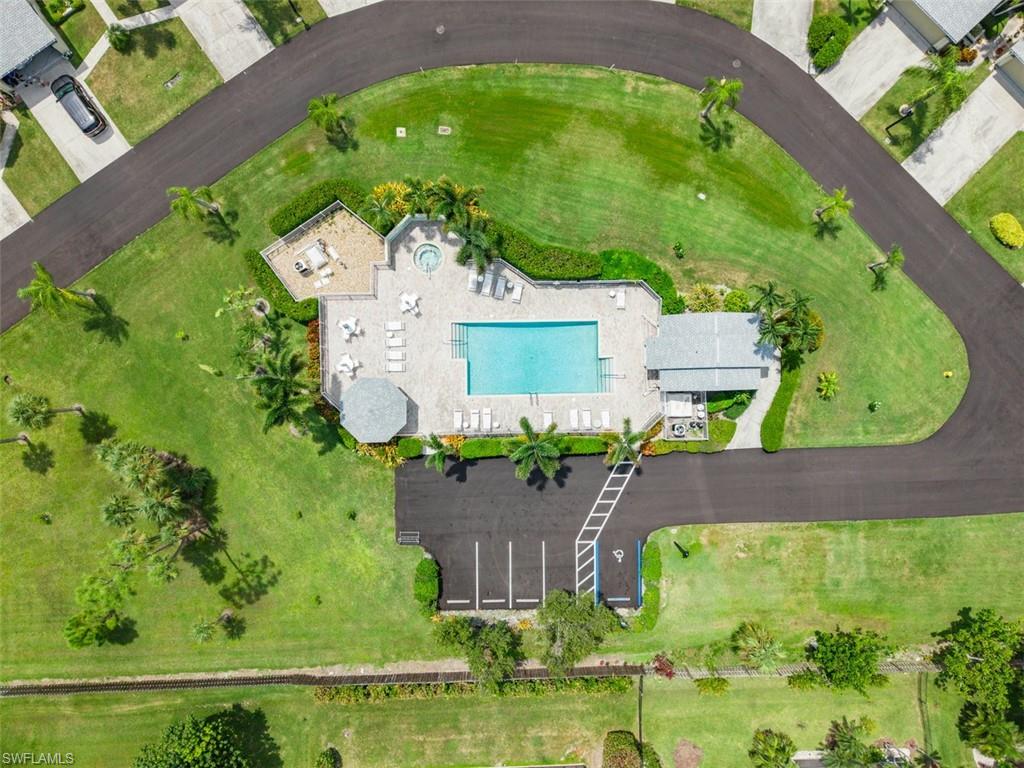 Community pool and spa area with surrounding green space, paved pathways, and an adjacent parking lot