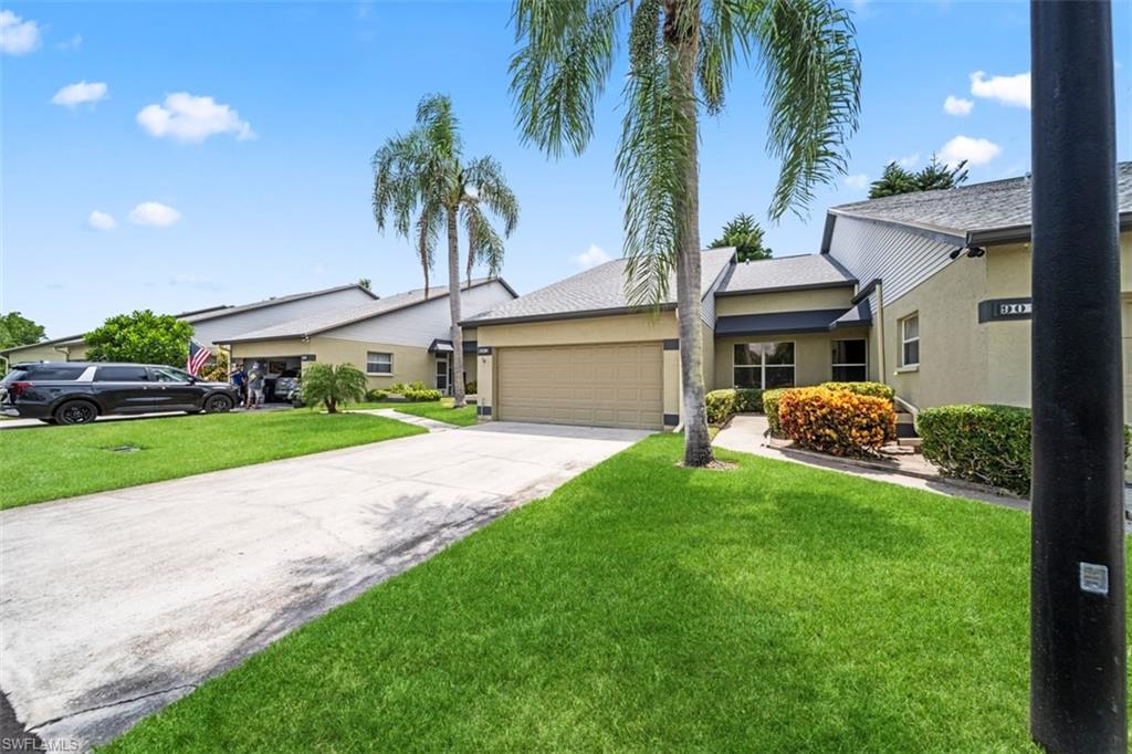 Stucco exterior with a pitched roofline, attached garage, and mature palm trees