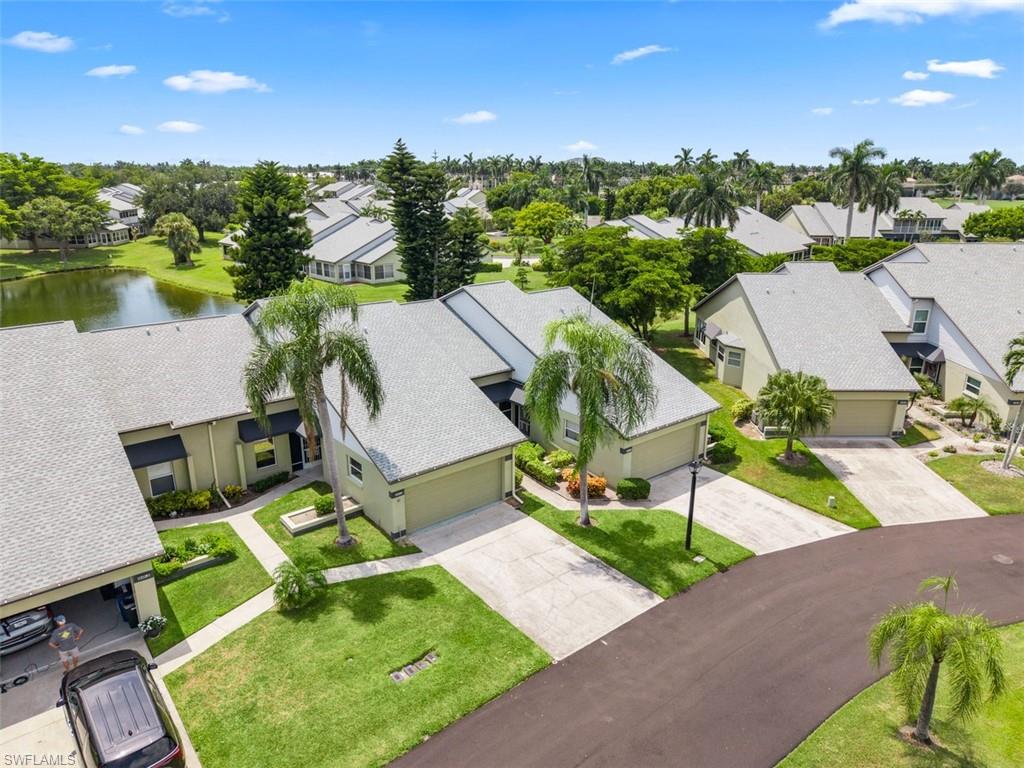 Paved driveway, attached garages, mature landscaping, shingle roof, and lake access
