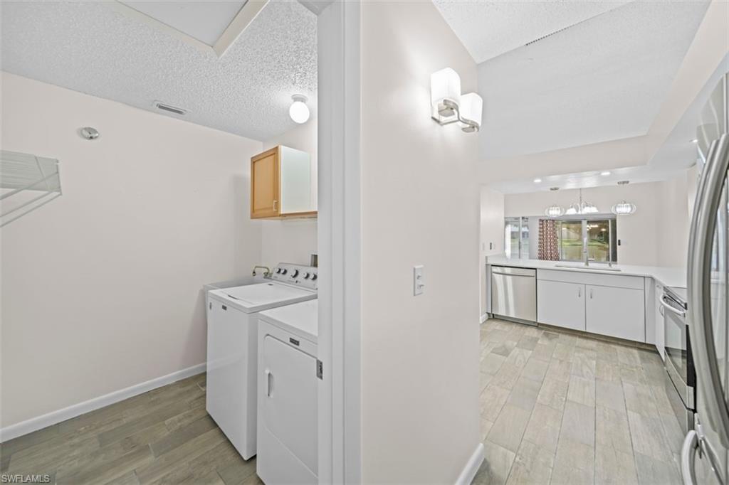 Laundry area with wood-finish flooring and upper cabinetry