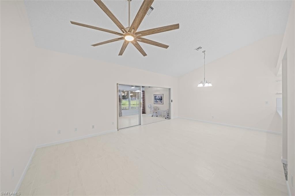 Vaulted ceilings, large sliding glass doors, contemporary ceiling fan, tile flooring, and a chandelier