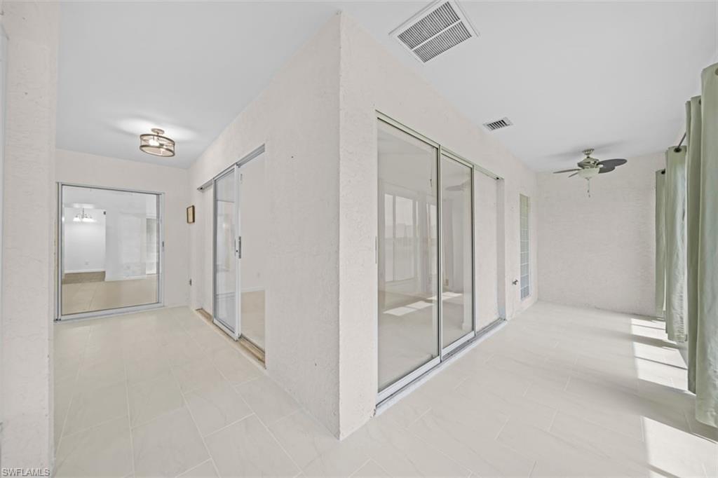 Tiled flooring throughout, sliding glass doors, ceiling-mounted light fixture, and a ceiling fan