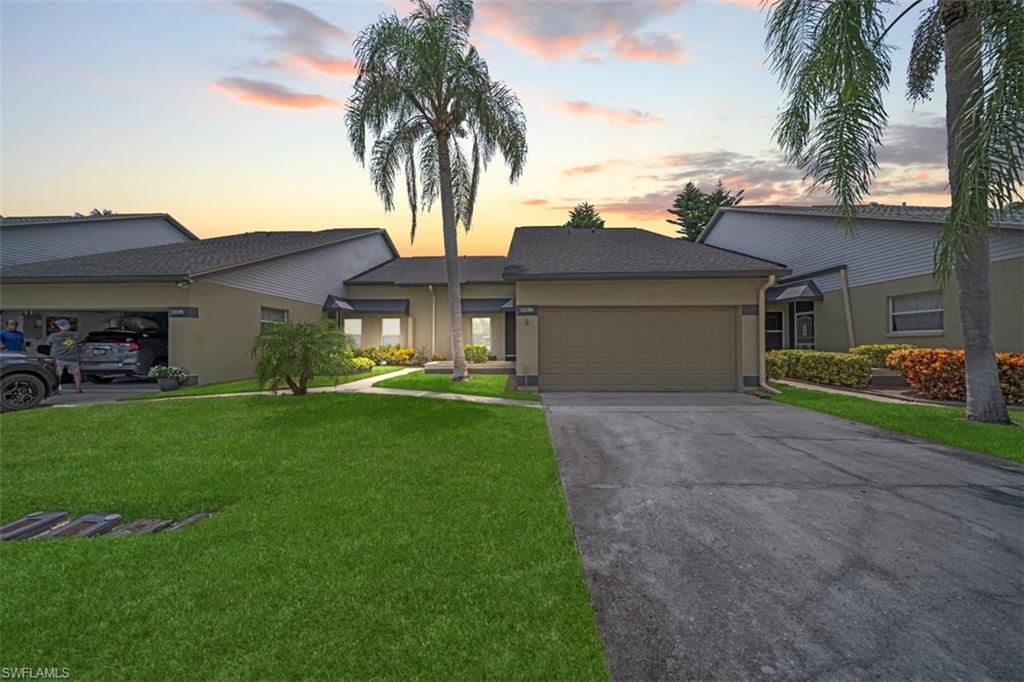 Single-story residence featuring an attached garage, paved driveway, and manicured front lawn