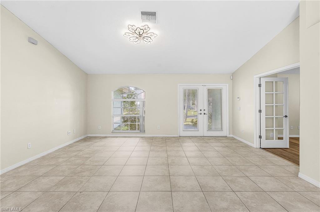 Vaulted ceilings, tile flooring, arched window, and French doors