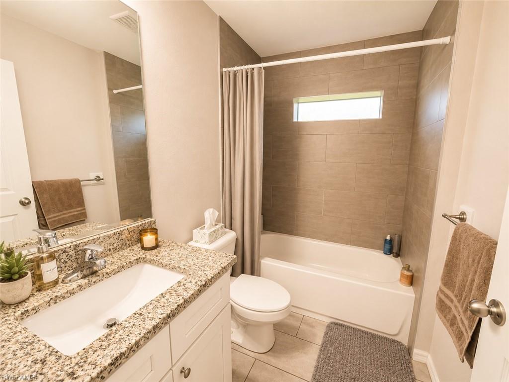 White vanity with a granite countertop, ceramic undermount sink, and chrome faucet