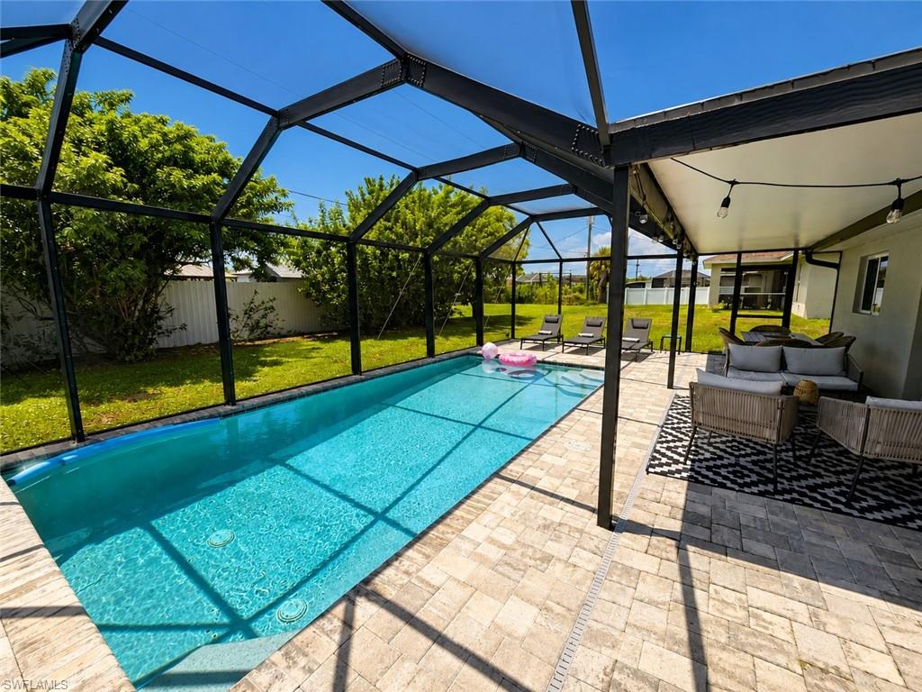 Screen-enclosed rectangular swimming pool with integrated steps, surrounded by a paved patio