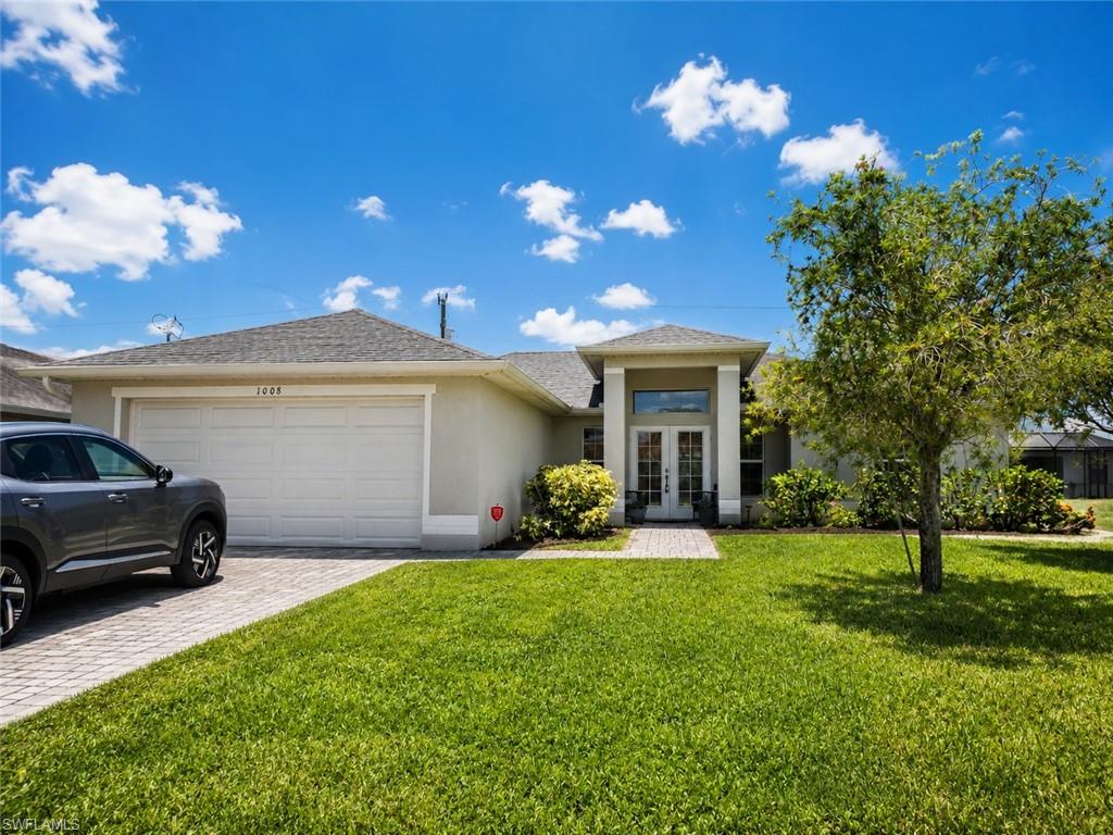 Stucco exterior with a hip roof, double entry doors, an arched transom window, and a paver driveway