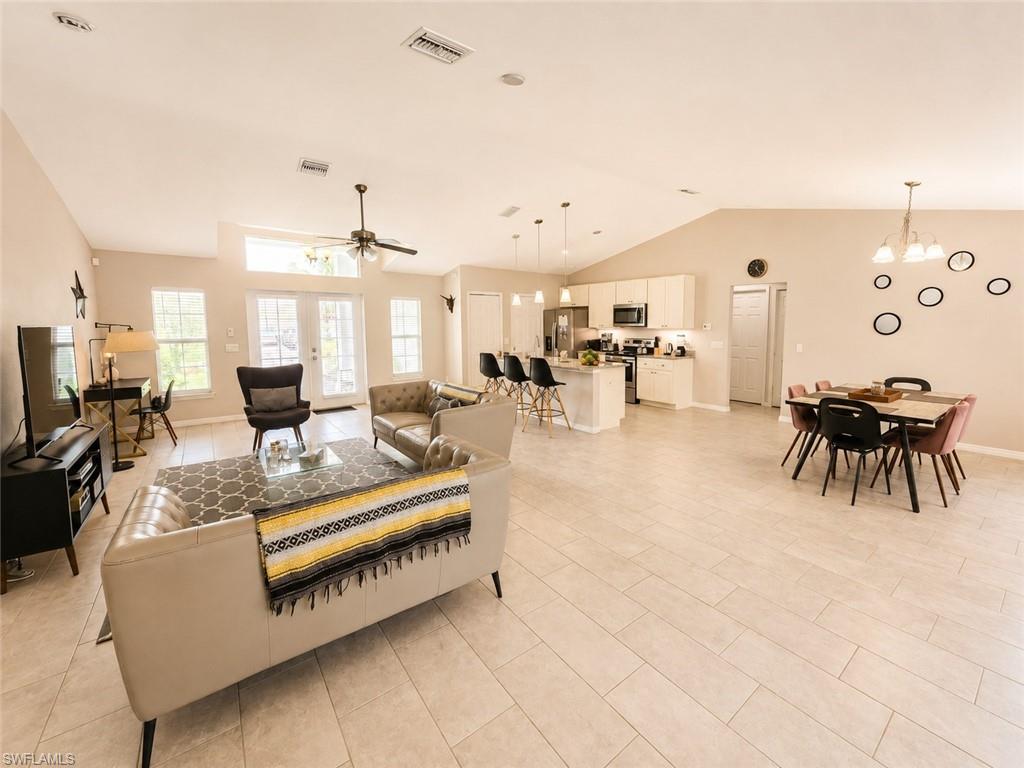 Vaulted ceilings, light-toned tile flooring, kitchen island with built-in cabinetry, pendant lighting, and double French doors