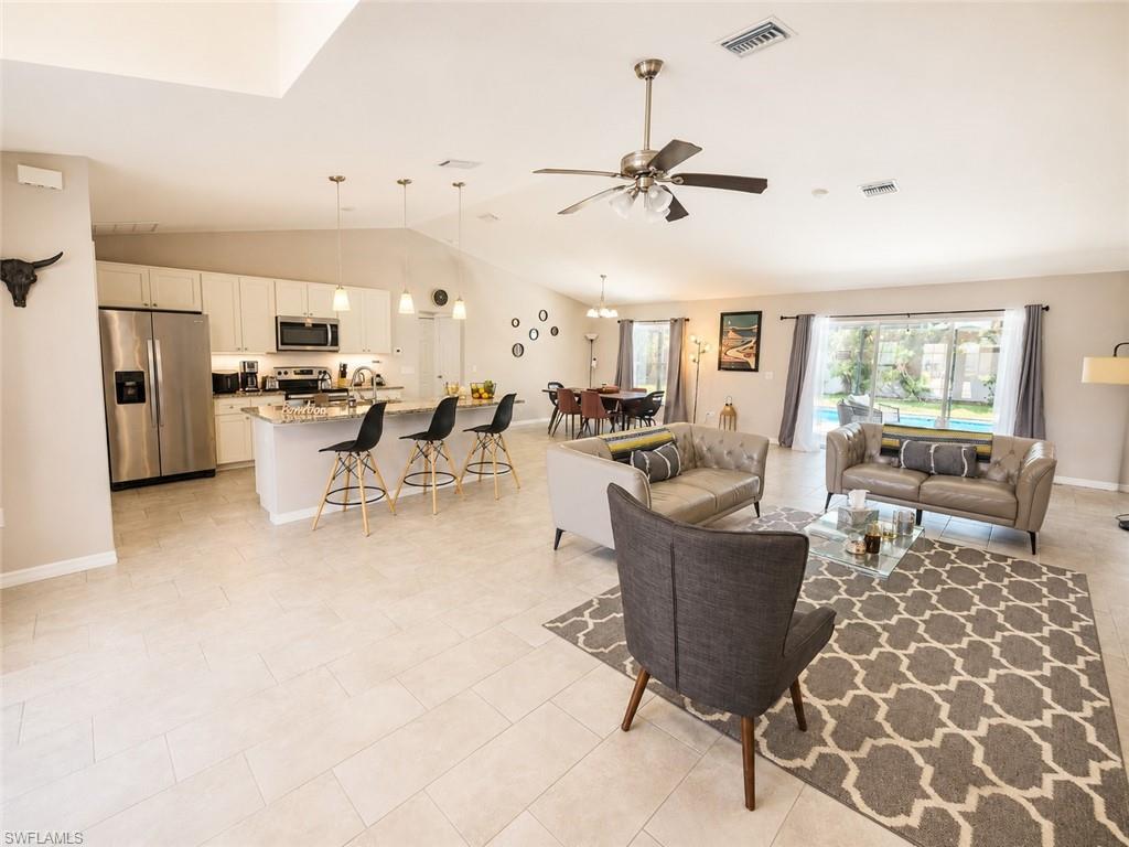 Vaulted ceilings with an open-concept layout, a kitchen island with pendant lighting, stainless steel appliances, and tile flooring throughout