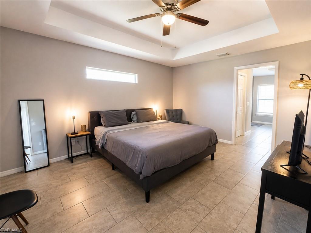 Tray ceiling with a ceiling fan, transom window, and tile flooring