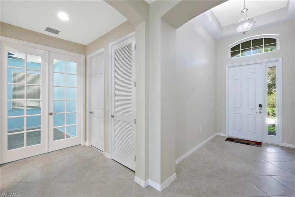 Foyer featuring a decorative front door with a transom window and sidelight, a tray ceiling with a chandelier, and diagonal tile flooring