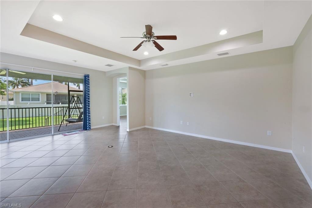Recessed lighting, ceiling fan, tray ceiling, tile flooring, and sliding glass doors