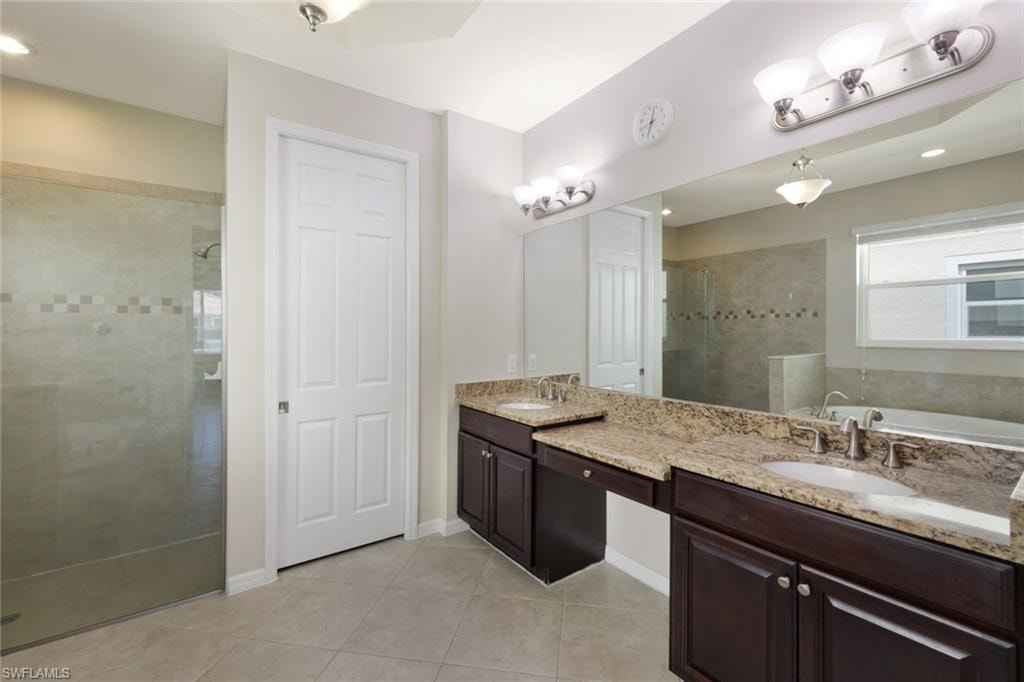 Dual vanity with granite countertops, wood-finish cabinetry, and brushed nickel fixtures