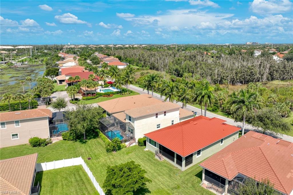 Aerial overview featuring multiple residential properties with tiled roofs, screened-in pools, and manicured lawns