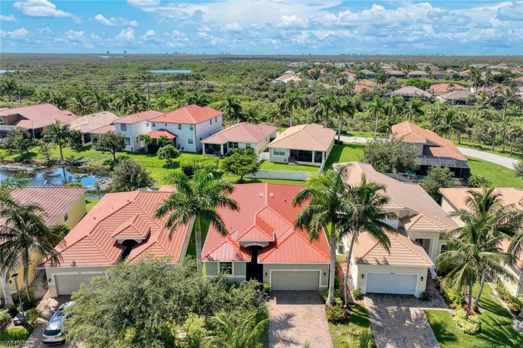 Residential property featuring a terracotta tile roof, attached garage, paved driveway, and mature palm trees