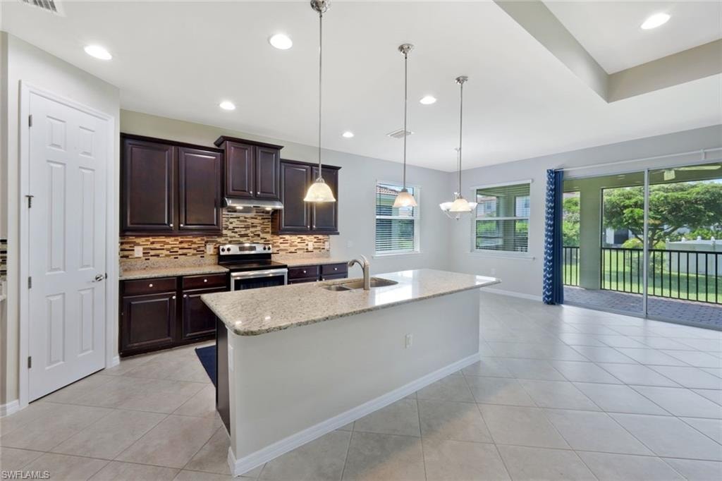 Kitchen featuring dark wood cabinetry, a tiled backsplash, and stainless steel appliances