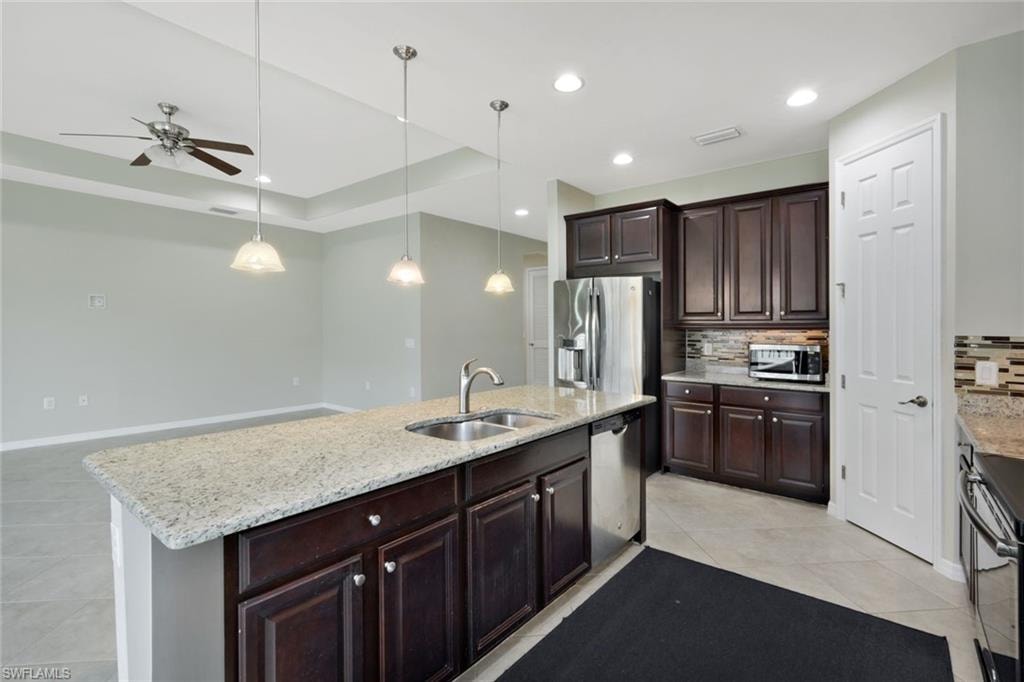 Kitchen featuring dark wood cabinetry, light-colored granite countertops, and stainless steel appliances
