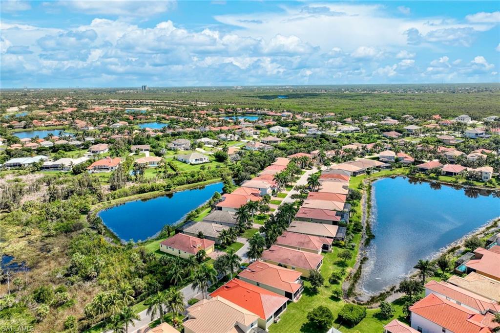 Residential community featuring multiple water bodies, mature landscaping, and a distant tree line