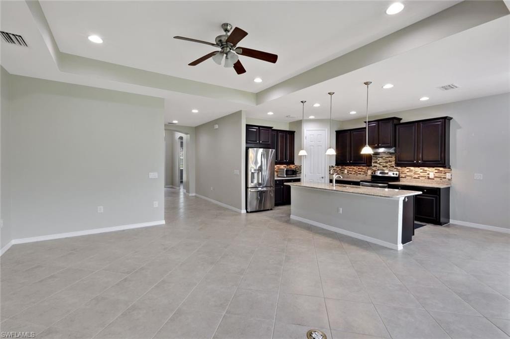 Open-concept living area featuring a kitchen with dark wood-finish cabinetry, stainless steel appliances, and a central island with pendant lighting