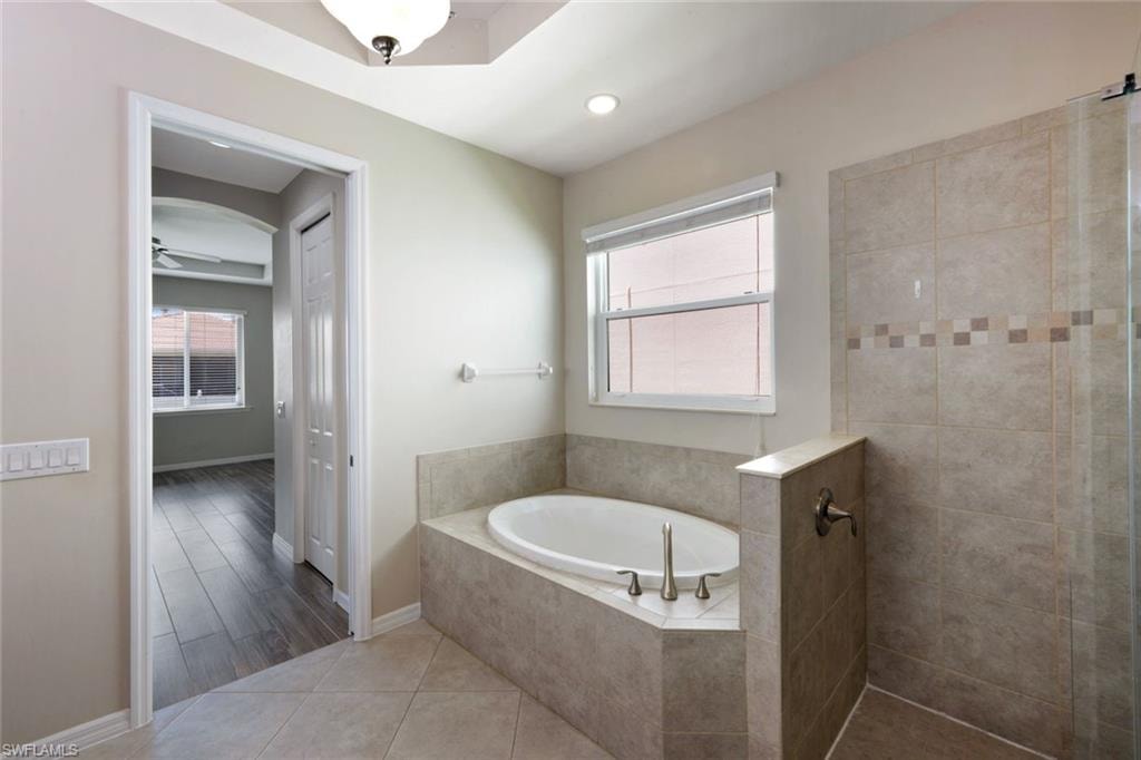 Spacious bathroom featuring a built-in soaking tub, tiled shower enclosure, and neutral-toned wall and floor tiling