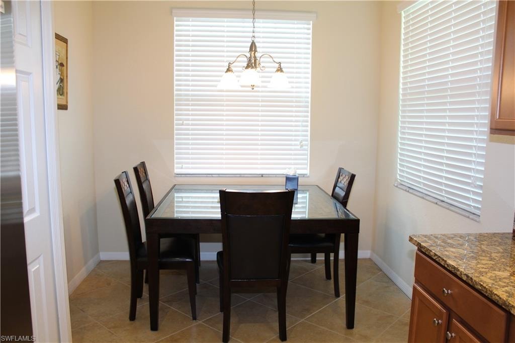 Dining space with light tile patterned flooring, plenty of natural light, and a chandelier