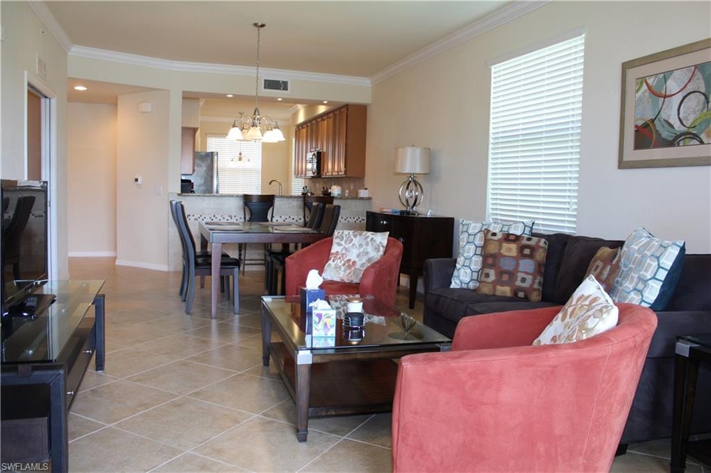 Living area featuring crown molding, light tile patterned flooring, and a chandelier