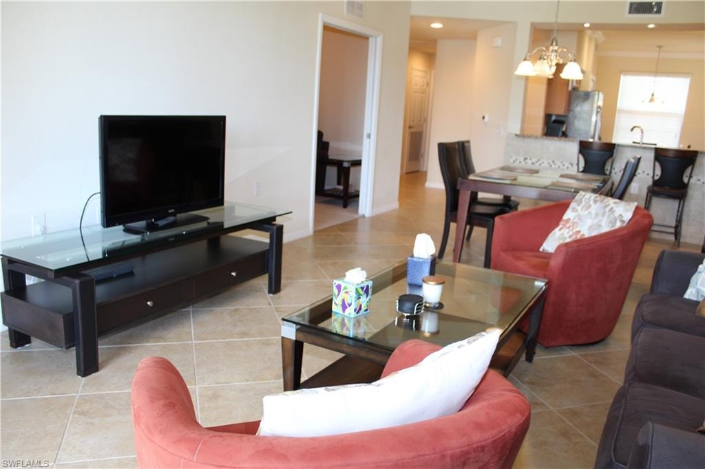 Living room with light tile patterned flooring, a chandelier, and recessed lighting