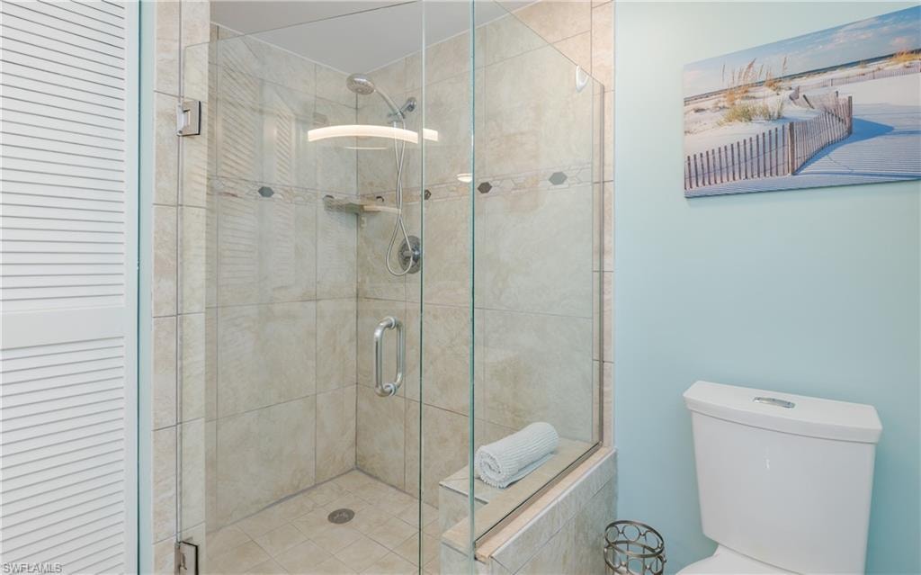 Glass-enclosed shower with a built-in bench, tiled walls, and a recessed niche