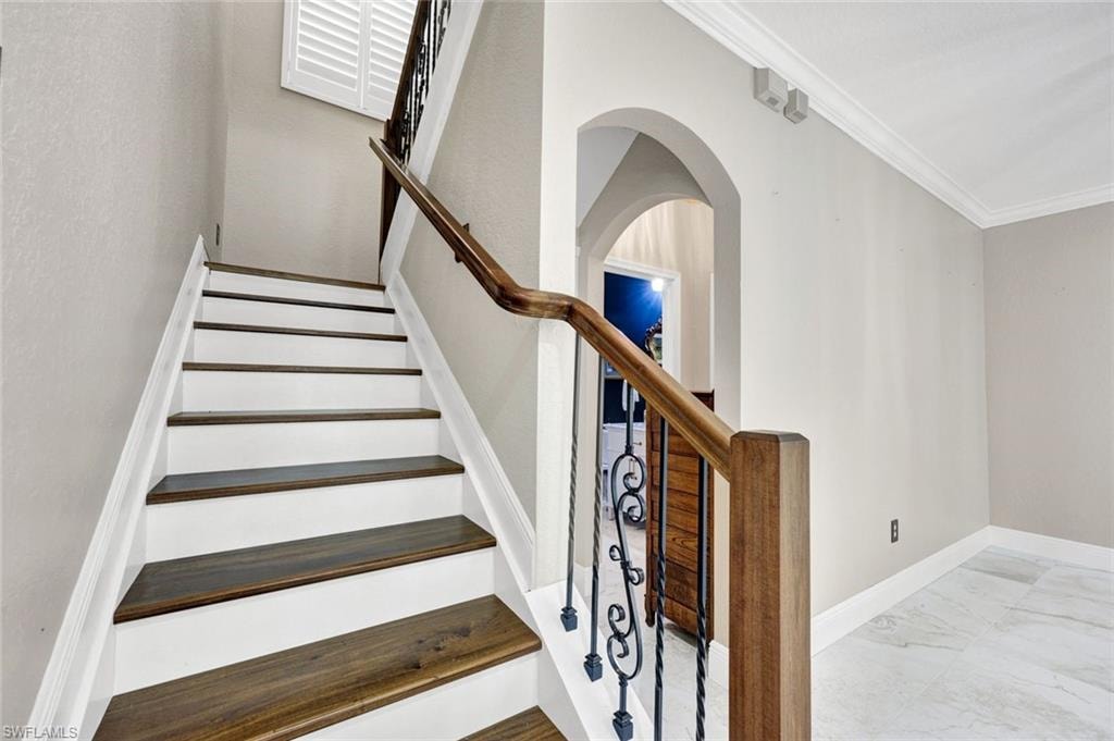 New and updated staircase with wood-finish treads, white risers, and a wrought iron railing with a wood-finish handrail
