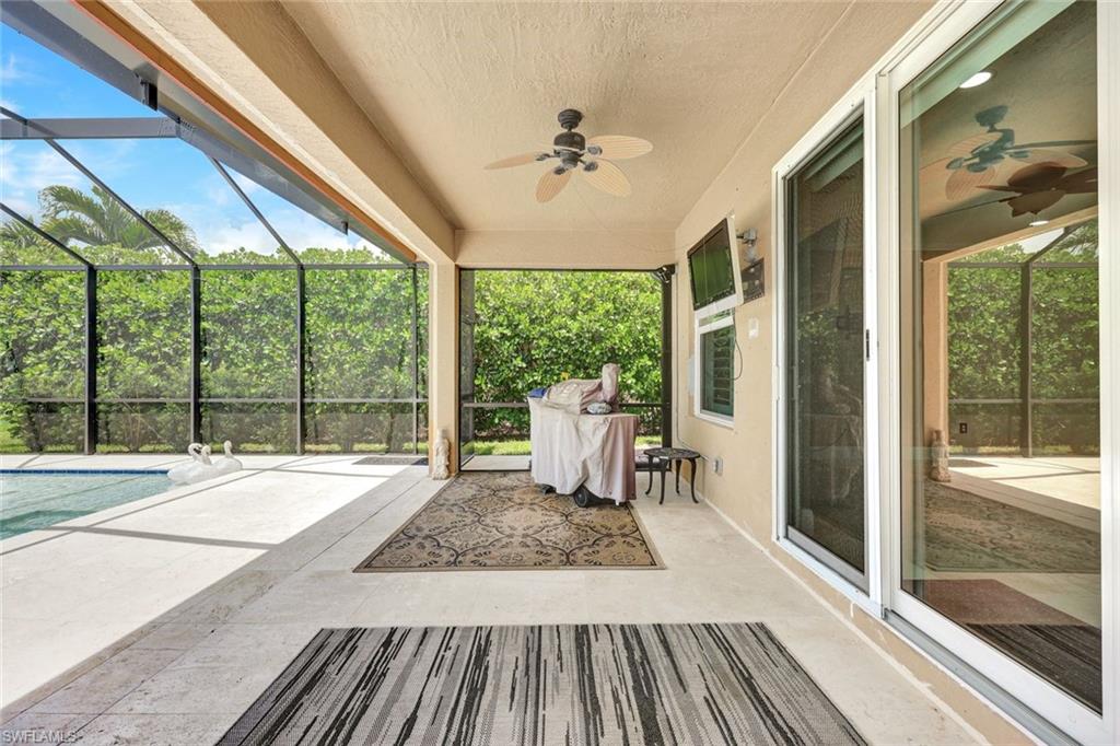 Screened outdoor living area with a ceiling fan, stone-finish flooring, and direct access to a pool