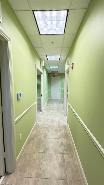 Hall featuring a drop ceiling and light tile patterned floors