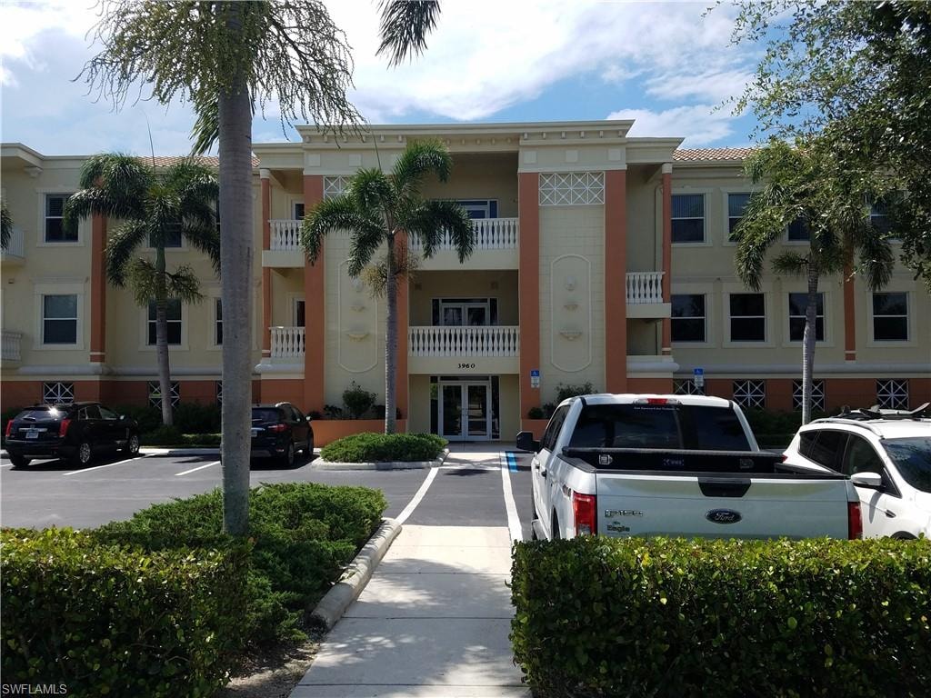 View of apartment building / complex featuring uncovered parking