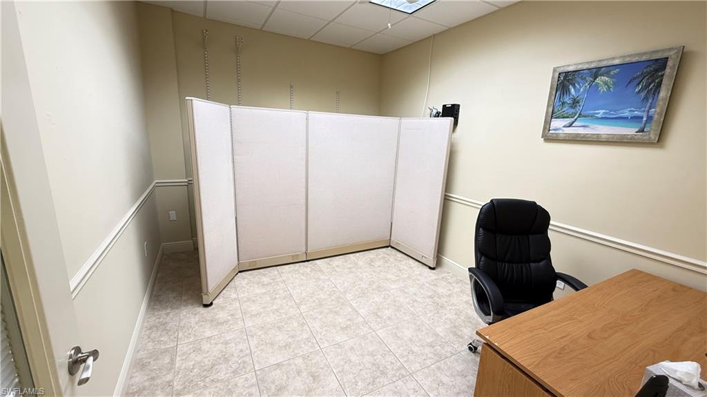 Office #1 area with a drop ceiling and light tile patterned floors