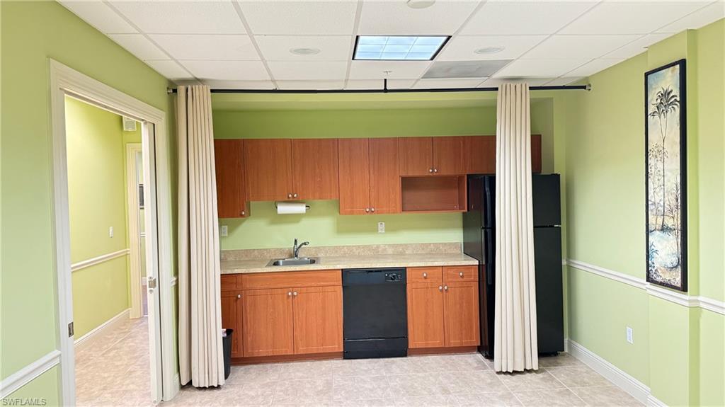 Conference/Instrutor room with Kitchen featuring light countertops, wood finish cabinets, black appliances, a drop ceiling, and light tile patterned flooring