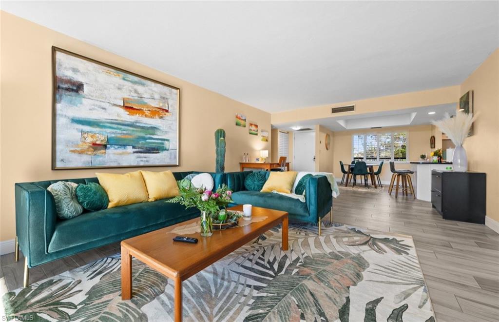 Open-concept living space featuring light-toned walls, recessed lighting, and wood-finish flooring