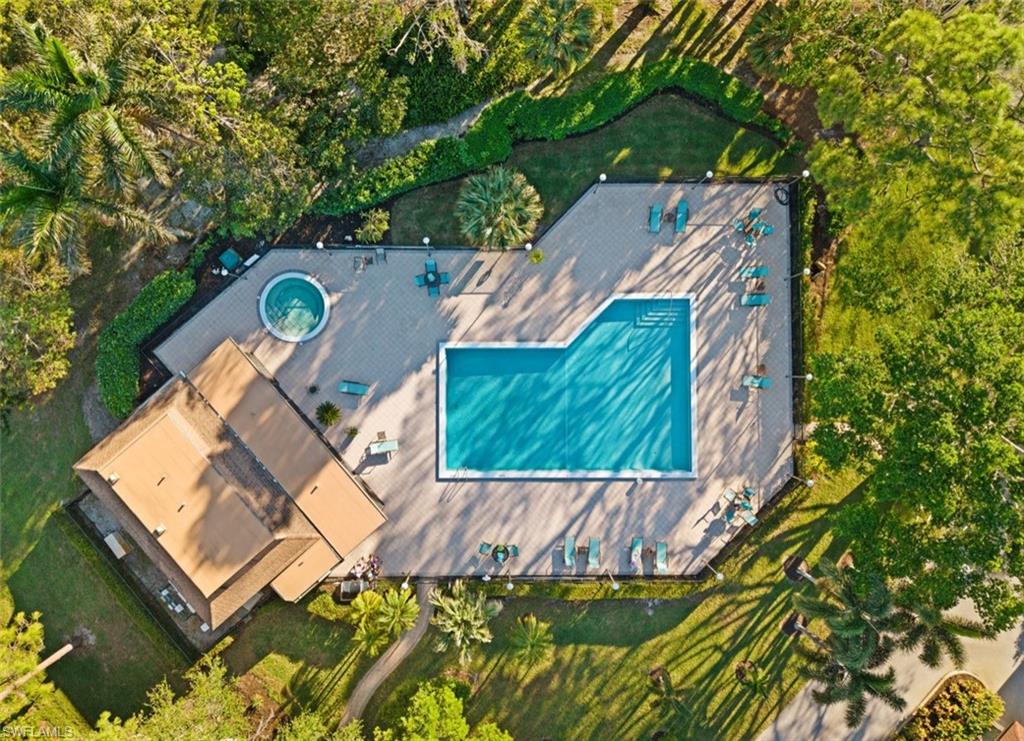 Outdoor swimming pool with surrounding paver deck, integrated hot tub, and established landscaping