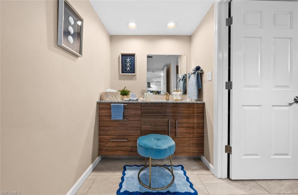 Modern floating vanity with a wood-finish cabinet and integrated sink, complemented by recessed lighting and neutral wall tones